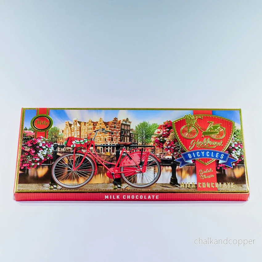 Chokladkaka LJUS förpackningen med avtryck av en röd cykel längs en kanal i Amsterdam (Chocoladereep MELK) Chokladkaka LJUS förpackningen med avtryck av en röd cykel längs en kanal i Amsterdam (Chocoladereep MELK)